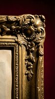 Ornate golden baroque frame corner with intricate carved floral scrollwork and decorative molding details on dark burgundy background for luxury interior design.