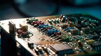 Close-up macro view of electronic circuit board with microchips, resistors, capacitors and copper traces. Technology hardware components for repair and engineering.