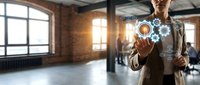 Professional businesswoman touching digital interface with gear icons in modern loft office space representing technology innovation and automation solutions.
