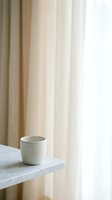 Minimalist ceramic cup on marble shelf with soft neutral curtains in background, suitable for home decor, lifestyle, and interior design projects.