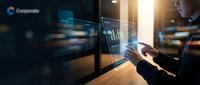 Professional businessman analyzing financial data on multiple computer monitors in modern office environment with warm lighting and technology focus.
