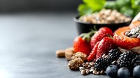 Fresh berries, nuts and seeds arranged on gray background with copy space. Healthy organic superfood mix with strawberries, blueberries and blackberries.