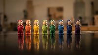 Colorful wooden peg people figures arranged in rainbow order on reflective surface representing diversity, teamwork and inclusion concepts.