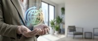 Professional businessman holding glowing digital globe hologram in modern office space representing global business connectivity and international commerce.