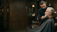 Barber trimming senior man's hair in traditional barbershop setting, professional grooming and haircut service for mature male clients.