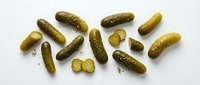 Whole and sliced dill pickles arranged on white background, ready for food styling, culinary content, recipe illustrations, restaurant menus, grocery packaging, and cooking websites.