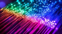 Vibrant fiber optic cables creating rainbow spectrum with glowing light effects, pink to blue gradient illumination against dark background for technology and communication concepts.