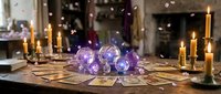 Mystical fortune telling setup with glowing crystal balls, tarot cards, and burning candles creating atmospheric divination scene for spiritual guidance sessions.
