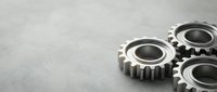 Three metallic gears with detailed teeth on brushed steel surface for industrial engineering and mechanical design projects.