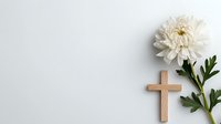 Wooden cross and white chrysanthemum flower on light background. Religious sympathy, memorial or funeral concept with copy space for text.