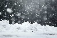 Falling snowflakes against dark winter background with accumulated snow on ground, creating atmospheric seasonal scene with bokeh effect and natural lighting.