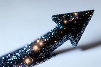 Glittering upward arrow shape with sparkling blue particles and golden light effects against blurred background, symbolizing growth, success and progress.