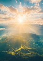 Dramatic aerial view of sunbeams breaking through clouds over mountain landscape, with golden light illuminating valleys and ridges during sunset.