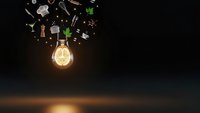Glowing light bulb with floating business icons representing innovation, creativity and entrepreneurship concepts on dark background.