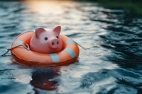 Pink ceramic piggy bank floating on orange life buoy in dark blue water, financial safety and emergency savings concept for banking and insurance.