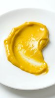 Bright yellow mustard sauce smear on white plate, ideal for food styling, culinary presentations, restaurant menus, and condiment advertising.