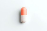 Single pharmaceutical capsule in coral pink and white colors on clean white background, isolated with soft shadow. Medical and healthcare concept.