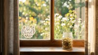 Cozy window sill with a be kind sticker and a glass jar of dried chamomile flowers, soft natural light, green garden bokeh background.