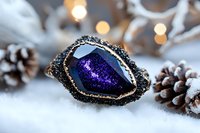 Luxury purple druzy geode slice with gold rim and black crystals on white fur with pinecones and warm bokeh lights for elegant jewelry display.