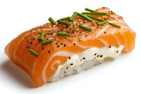 Fresh salmon nigiri sushi topped with cream cheese, chives and black sesame seeds on white rice, photographed on white background with soft shadows.