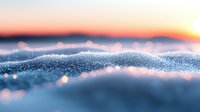 Macro shot of crystalline snow surface at sunset with dreamy bokeh effect and orange sky, creating abstract winter landscape with soft focus foreground details.