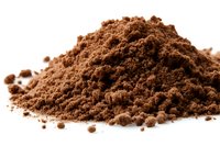 Fresh ground cocoa powder heap on white background, rich brown color with natural texture and shadows, isolated for food photography and packaging design.