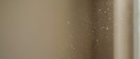 Abstract golden brown gradient background with floating dust particles and soft bokeh light effects for modern design projects.