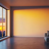 Modern empty room interior with large window overlooking city skyline at sunset. Warm orange lighting creates cozy atmosphere for residential design.