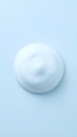 White cosmetic cream swirl on light blue background for skincare and beauty product advertising.