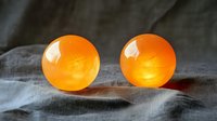 Glowing orange spherical balls on gray textile surface with soft illumination and dramatic shadows creating mysterious atmosphere.