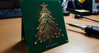 Green Christmas card with golden foil Christmas tree design on office desk. Holiday greeting card for seasonal marketing, corporate gifts, festive stationery.
