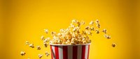 Red and white striped popcorn container with kernels bursting out against bright yellow background for entertainment and snack advertising concepts.