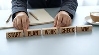 Business strategy concept with wooden blocks spelling START PLAN WORK CHECK WIN on desk. Professional planning and goal achievement methodology for success.