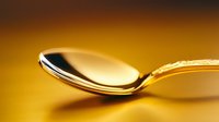Elegant golden spoon on warm amber background with dramatic lighting and reflective surface creates luxurious dining atmosphere for food and restaurant concepts.