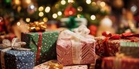 Festive wrapped Christmas presents with colorful paper and ribbons against blurred holiday lights background.