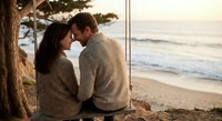 Romantic couple embracing on beach swing at sunset, intimate moment by ocean waves, cozy sweaters, golden hour lighting for wedding anniversary content.