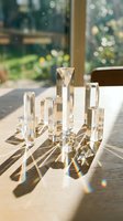 Clear crystal glass prisms arranged on a wooden table casting rainbow light refractions in sunlight, with a blurred garden background.