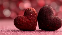 Two sparkling red glittery hearts on pink surface with bokeh lights background for Valentine's Day romance love celebration greeting cards.