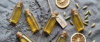Natural essential oil bottles with cork stoppers arranged on linen fabric with dried lavender sprigs and citrus slices for aromatherapy and wellness.