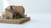 Miniature wooden house model with solar panels on roof displayed on wooden platform against white background for sustainable architecture concepts.