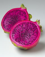 Fresh dragon fruit halves showing vibrant magenta flesh with black seeds, green outer skin visible. Close-up on white background for food and wellness content.