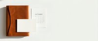 Minimalist October calendar page with brown leather notebook on neutral background for planning and organization.
