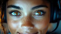 Close up portrait of young mixed race woman with freckles and striking amber eyes glowing in blue light, wearing headphones, expressing joy and confidence.