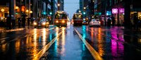 Wet city street at night with colorful neon reflections on asphalt, urban traffic and glowing storefronts creating atmospheric downtown scene for modern lifestyle concepts.