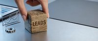 Business professional holding wooden block with LEADS text for marketing strategy and customer acquisition in modern office environment.