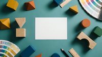 Blank white card mockup surrounded by colorful wooden blocks and paint swatches on teal background, flat lay design concept.