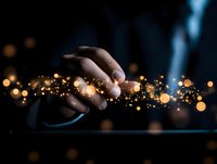 Magical glowing particles flowing from hand touching digital tablet screen in dark room with bokeh lights, representing digital transformation and innovation.