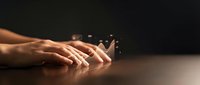 Hands of a middle-aged Caucasian woman gently touching a paper boat on a dark surface, symbolizing fragility, hope, and new beginnings for editorial and conceptual projects.