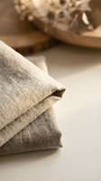 Natural linen fabric folded in soft beige tones with rustic texture for sustainable fashion and home decor projects on neutral background.