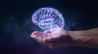 Glowing holographic brain floating above open palm against dark background. Concept for artificial intelligence, neuroscience, mental health and innovation.